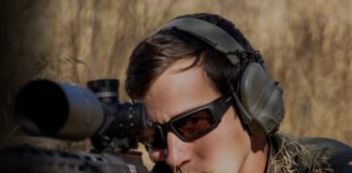 Man holding a rifle and wearing Revision's aluminum eyewear